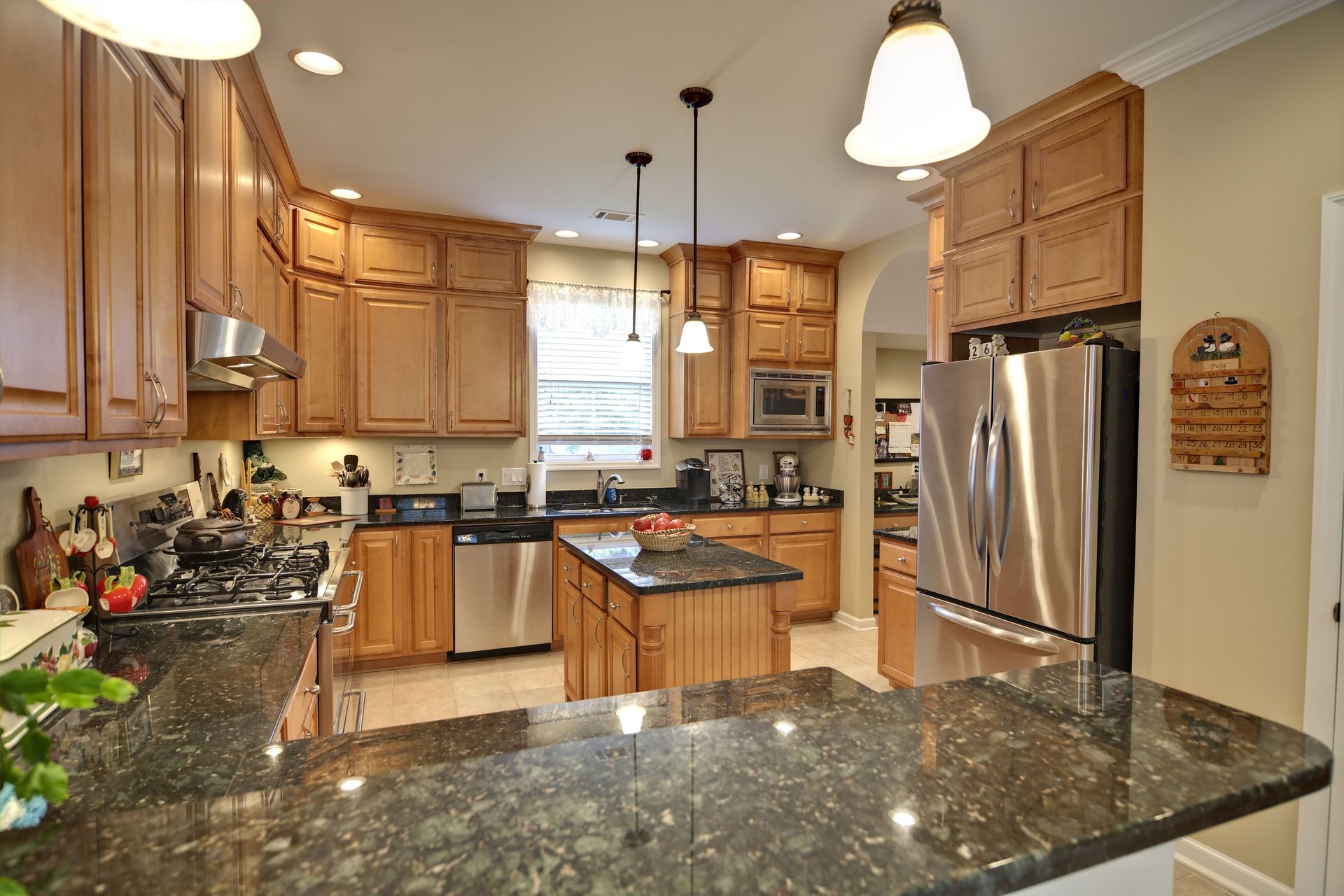 Spacious kitchen with wood cabinets, dark countertops, stainless steel appliances, and a central island.