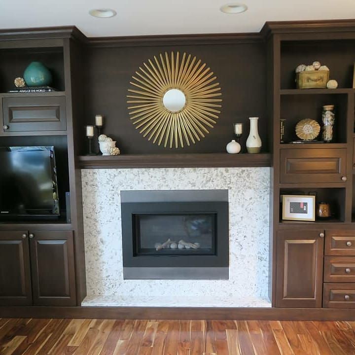 Built-in entertainment center with fireplace. Dark wood cabinetry surrounds a fireplace with gold sunburst mirror.
