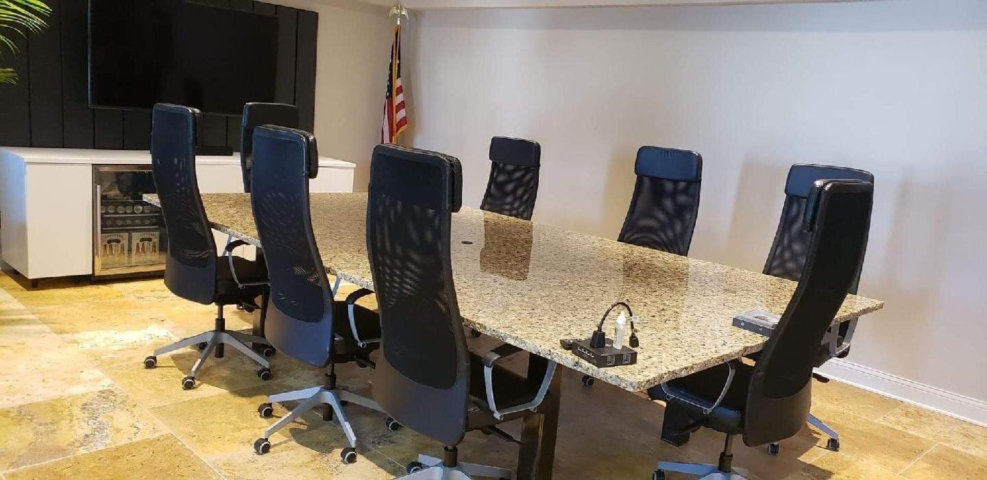 A conference room with a long table, black chairs, and a US flag.
