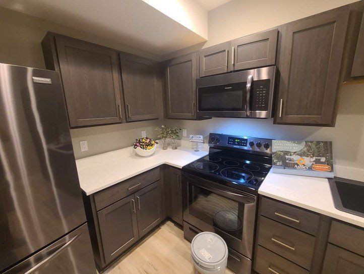 Kitchen with dark wood cabinets, stainless steel appliances, and white countertops.