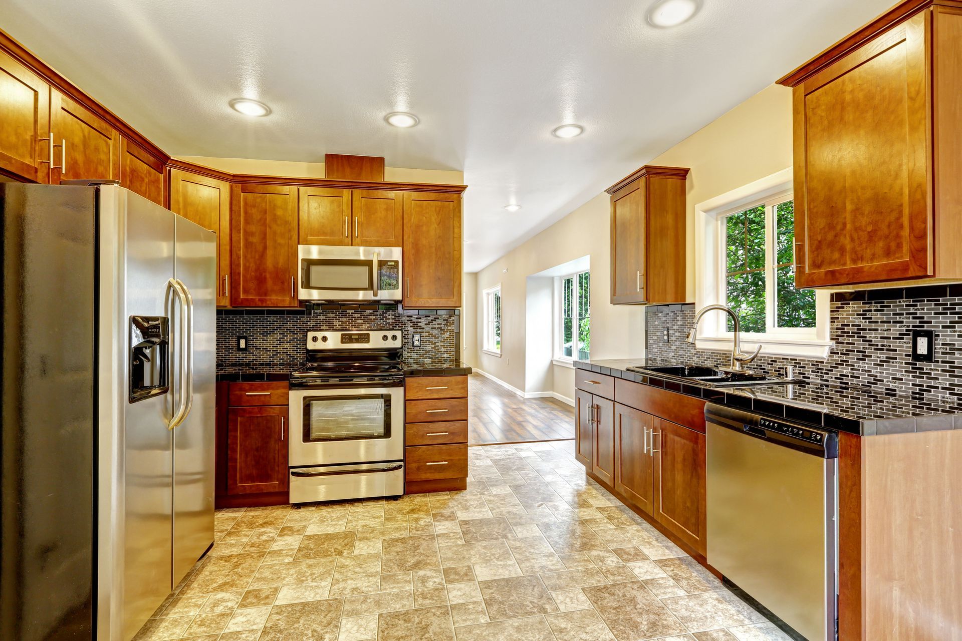 Kitchen with wood cabinets, stainless steel appliances, and patterned floor.