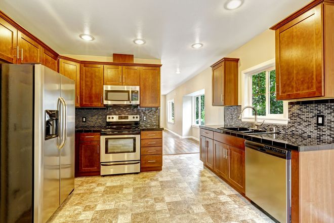 Kitchen with wood cabinets, stainless steel appliances, and patterned floor.
