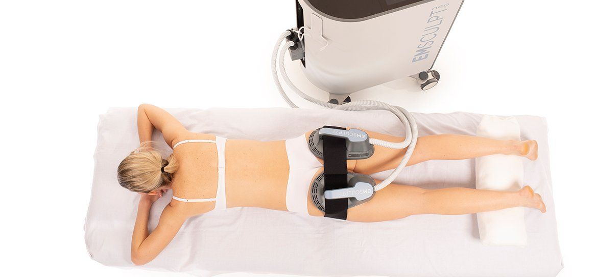 A woman is laying on a bed with a machine on her back.