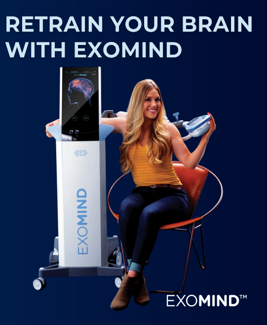 A woman is sitting in a chair next to a machine that says exomind