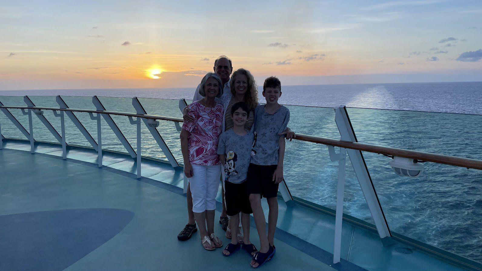 A family is posing for a picture on the deck of a cruise ship.