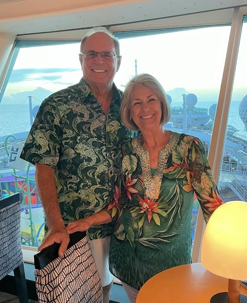A man and a woman are posing for a picture in front of a window.