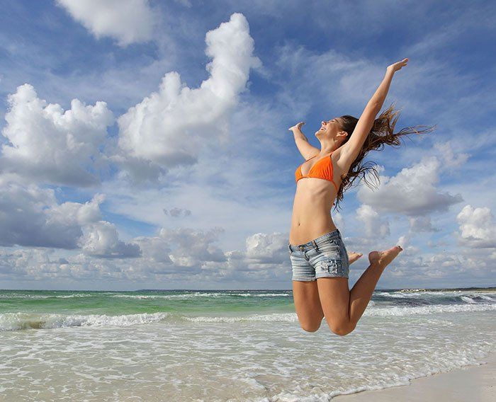 A woman in a bikini is jumping in the air on the beach