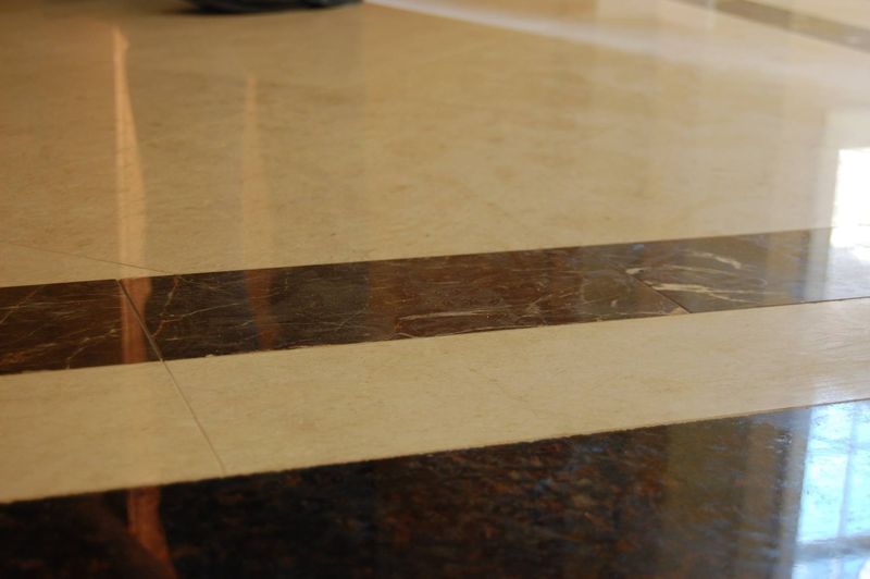 Polished marble floor with beige tiles and dark brown stripes reflecting light