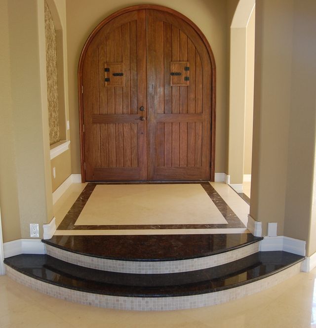 Stone entryway with a curved step leading to tall wooden double doors