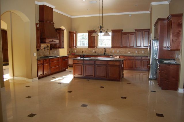 Spacious modern kitchen with dark wood cabinets, granite island, and beige tile floor