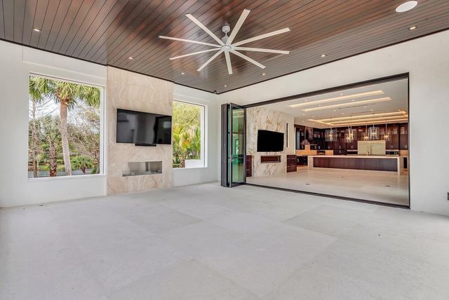 Modern covered patio with ceiling fan, TV, and open view into a kitchen and lounge area