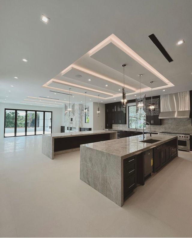 Modern luxury kitchen with large island, marble finishes, black accents, and bright open floor plan