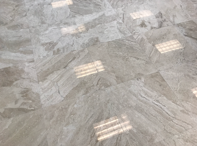 Polished gray marble floor with reflections of overhead lights.