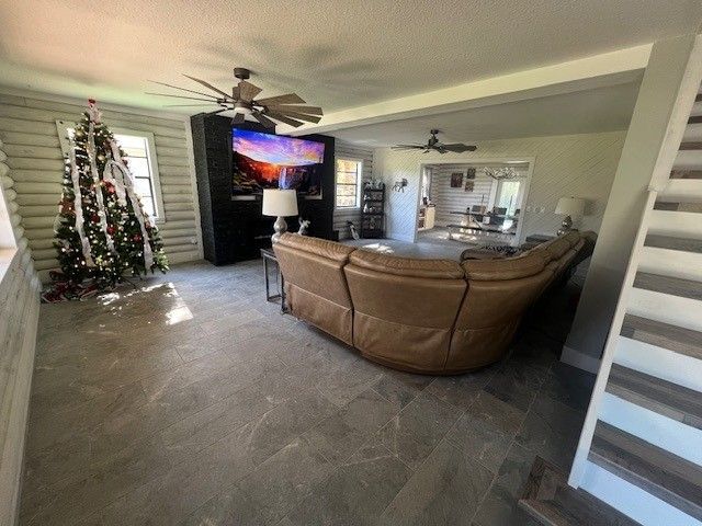 Bright living room with a large brown sectional, wall-mounted TV, decorated Christmas tree, and gray tile floor