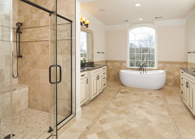 Luxury bathroom with glass shower, freestanding tub, and beige tile floor