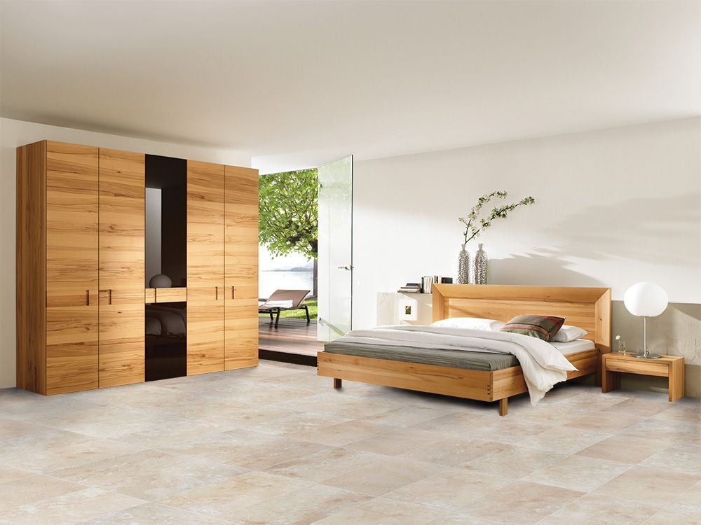 Modern bedroom with wooden furniture, a bed, wardrobe, and open door to a bright outdoor patio