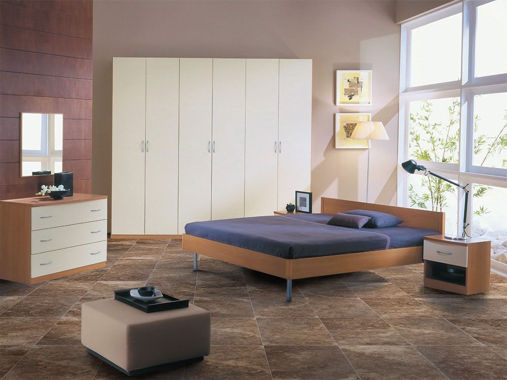 Modern bedroom with a large bed, white wardrobe, dresser, and windows letting in sunlight.