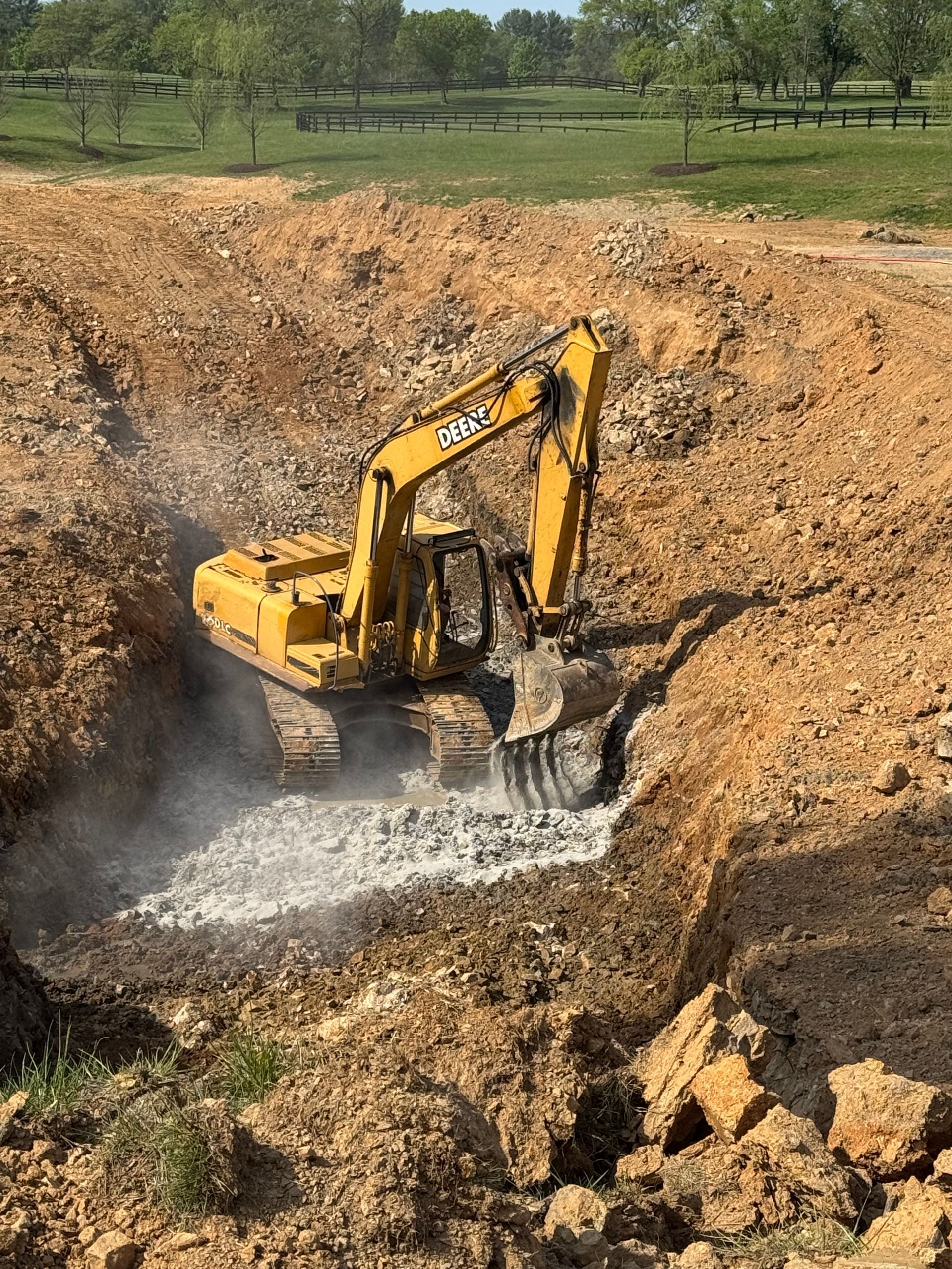 Yellow excavator digging into a brown earth pit.