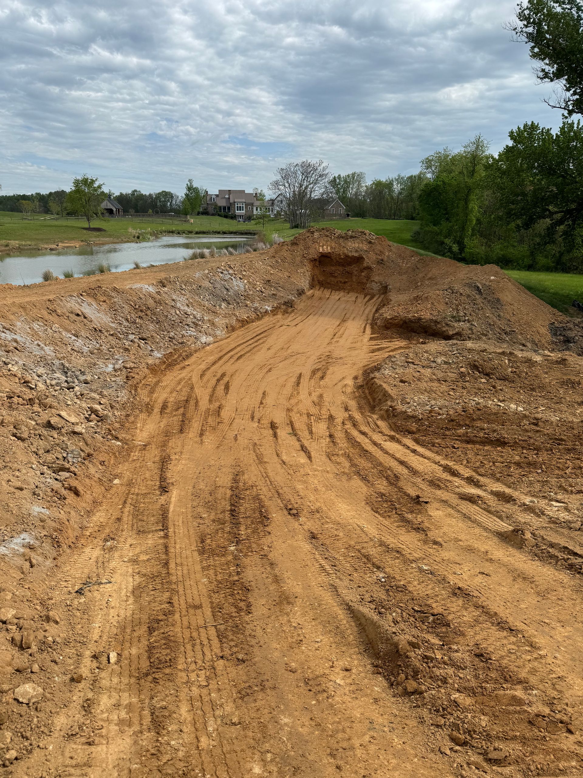 Muddy construction site with a path and a body of water in the background.