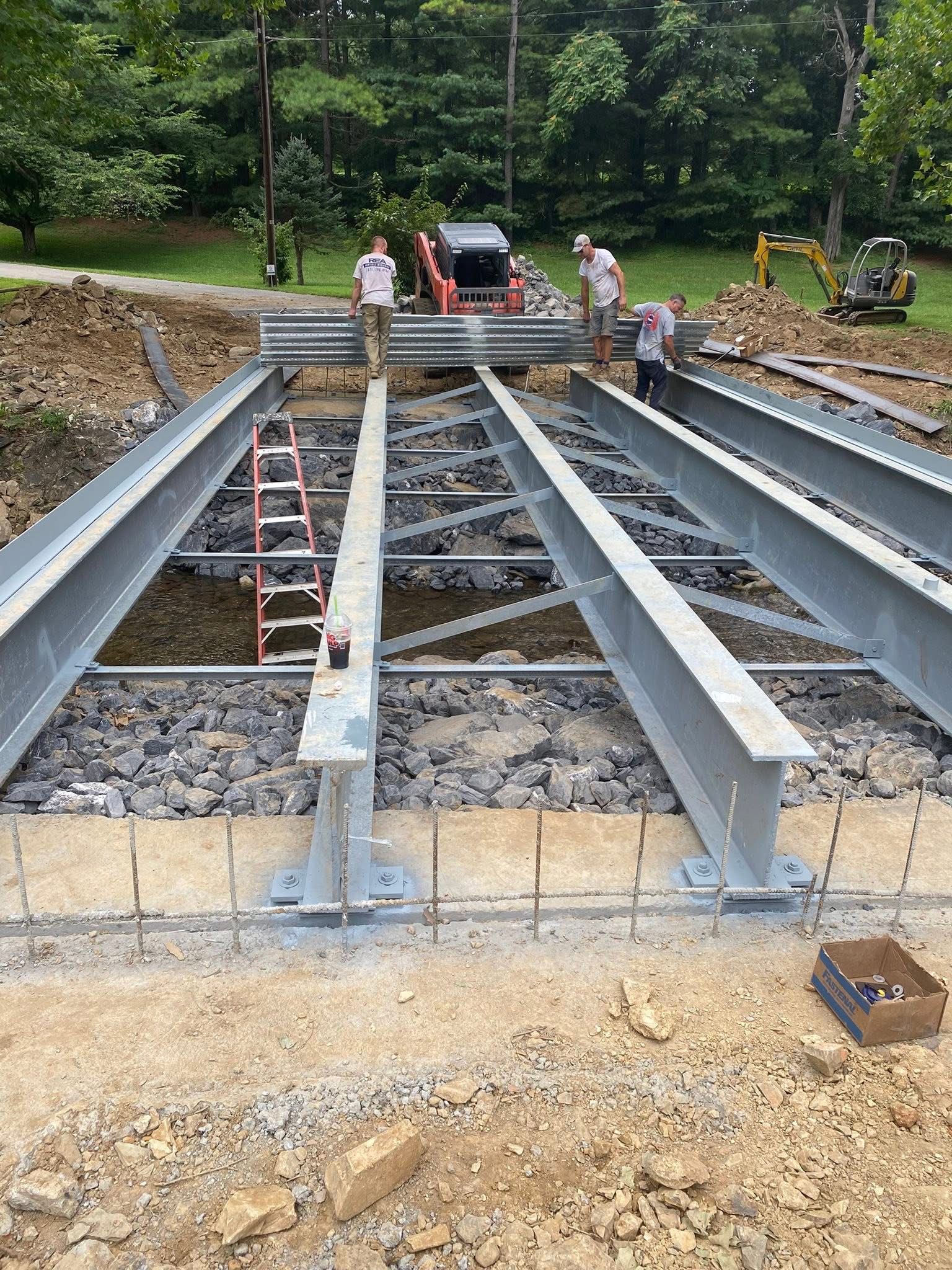 Construction site with steel beams, workers, and heavy machinery.