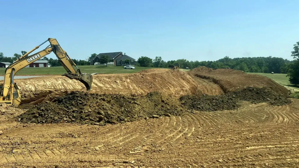 Excavator moving dirt in a construction site on a sunny day.
