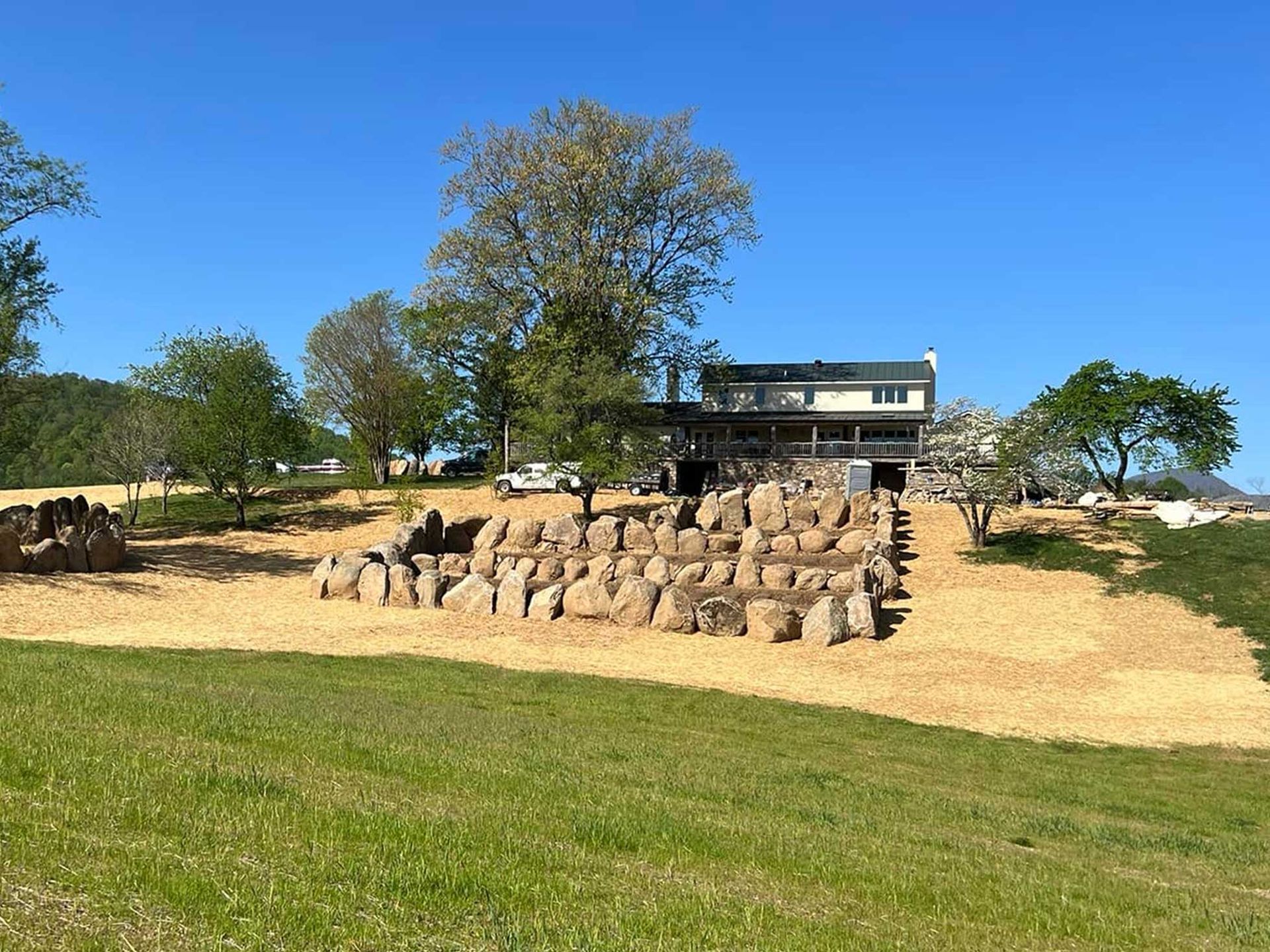 Building with stacked rock feature and landscaping on a grassy hill under a blue sky.