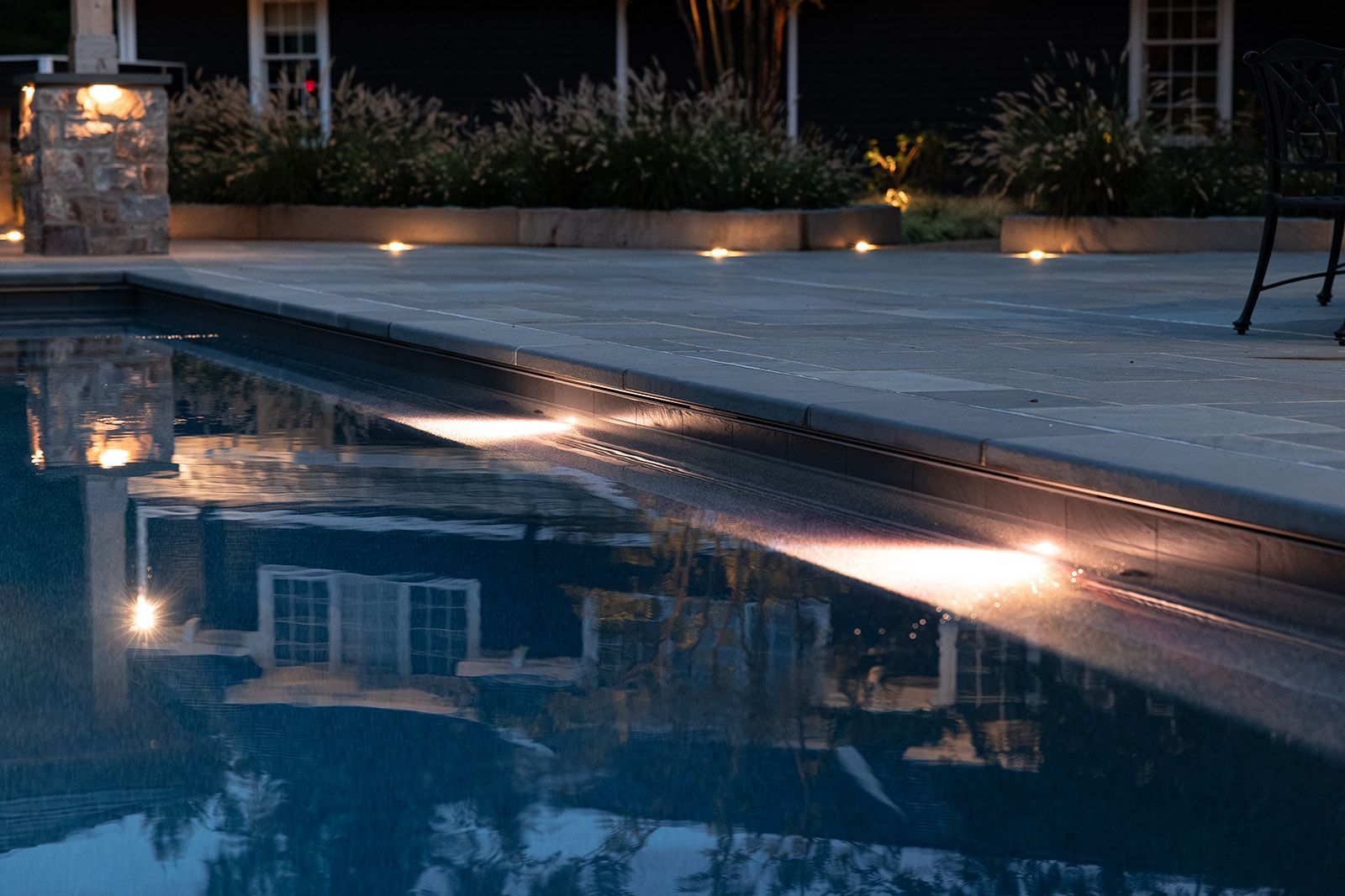 Dimly lit swimming pool reflecting a building and lights at dusk