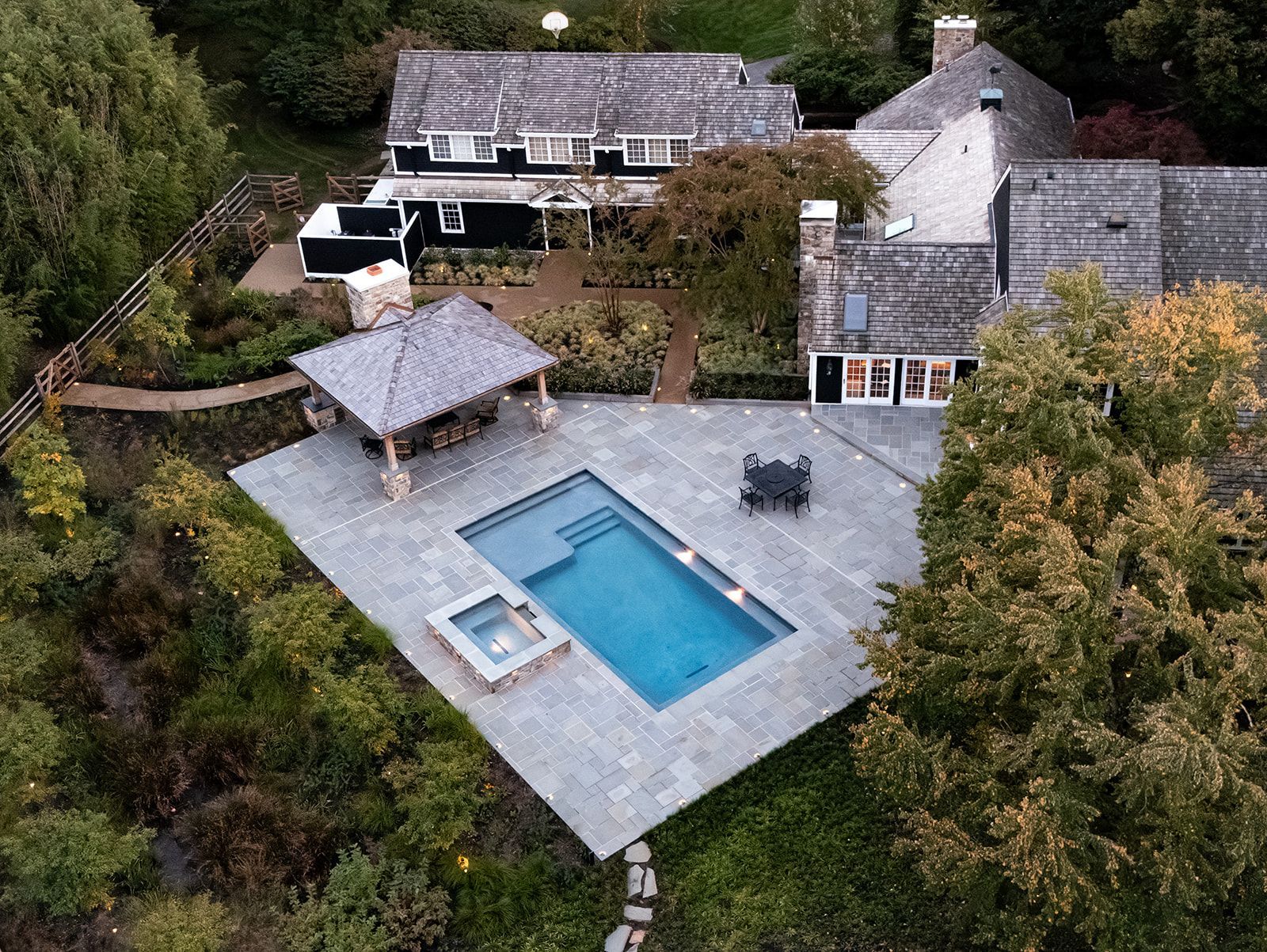 Aerial view of a house with a patio, swimming pool, and surrounding trees.