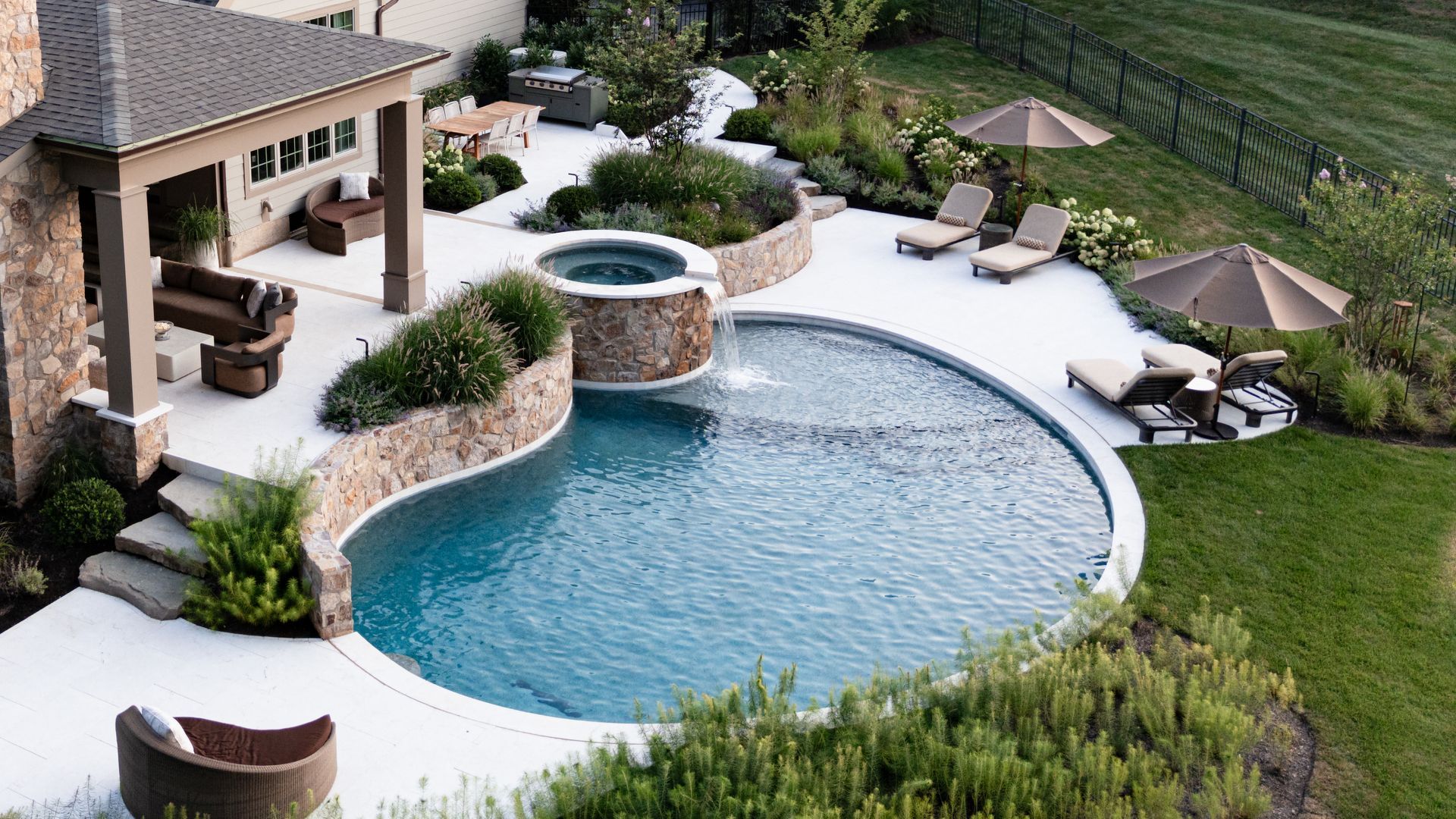 Backyard pool with spa, lounge chairs, and landscaping.