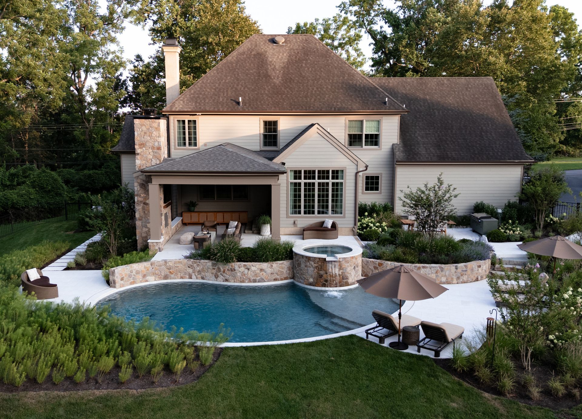 Luxury home exterior with pool, patio, and lush landscaping.