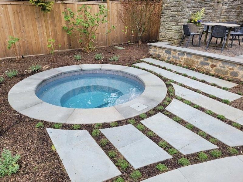 Circular hot tub with stone steps and garden setting.