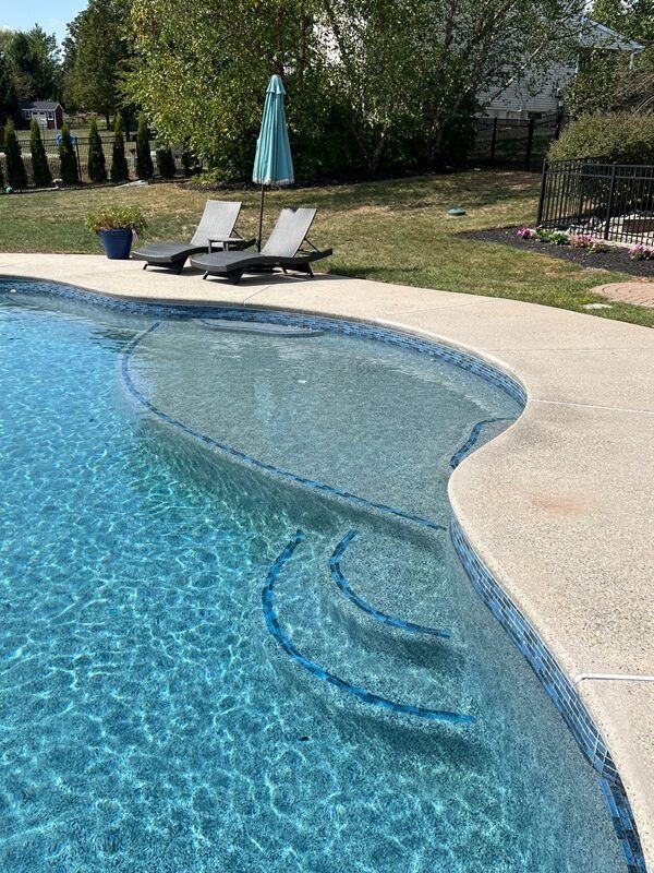 Swimming pool with steps, turquoise water, and lounge chairs. Sunny outdoor setting.