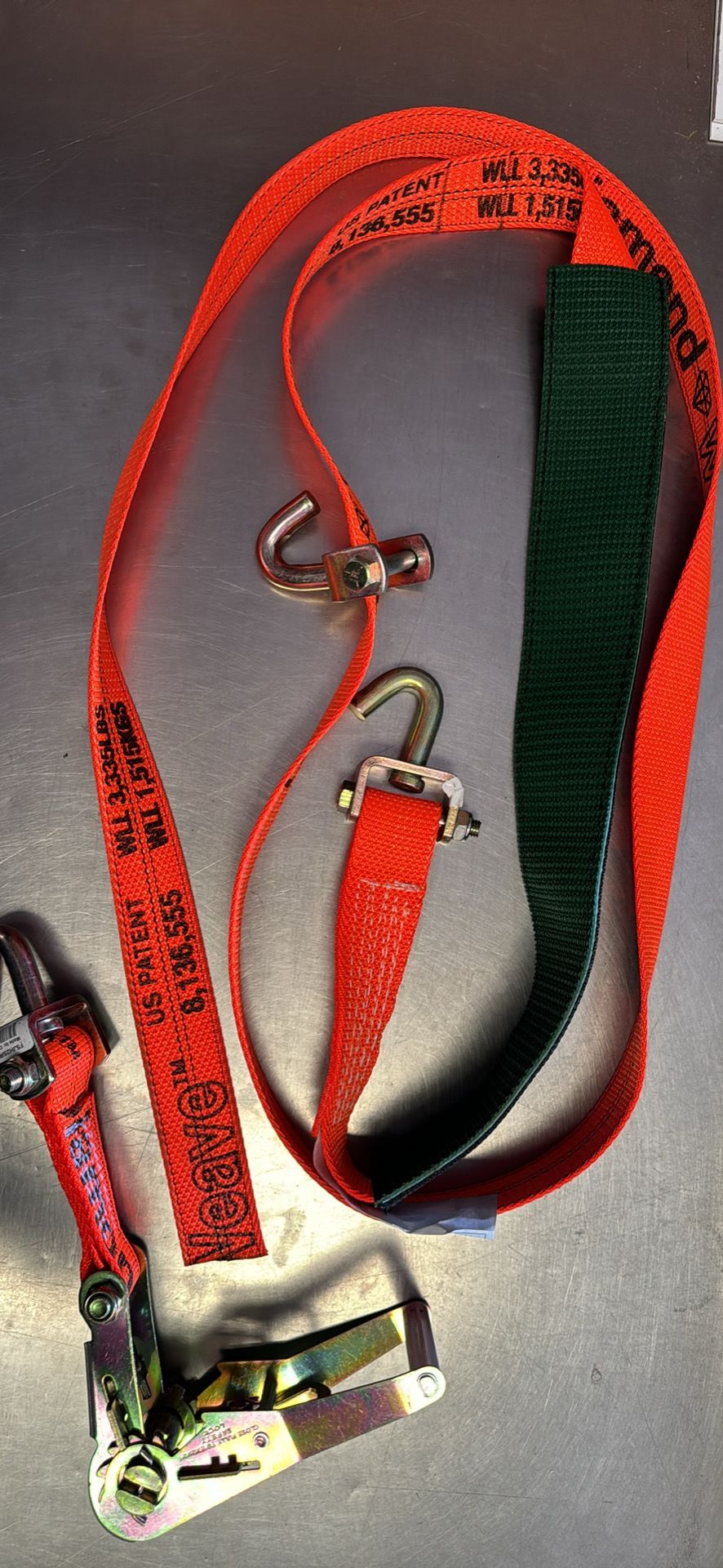 Red and green climbing harness straps with metal buckles on a dark surface