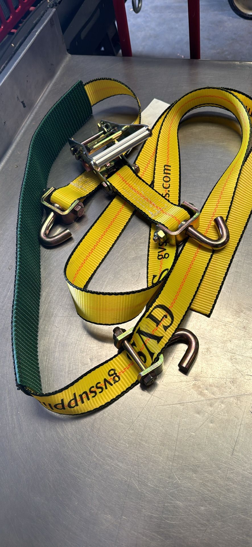Yellow safety harness with metal buckles and straps coiled on a gray floor