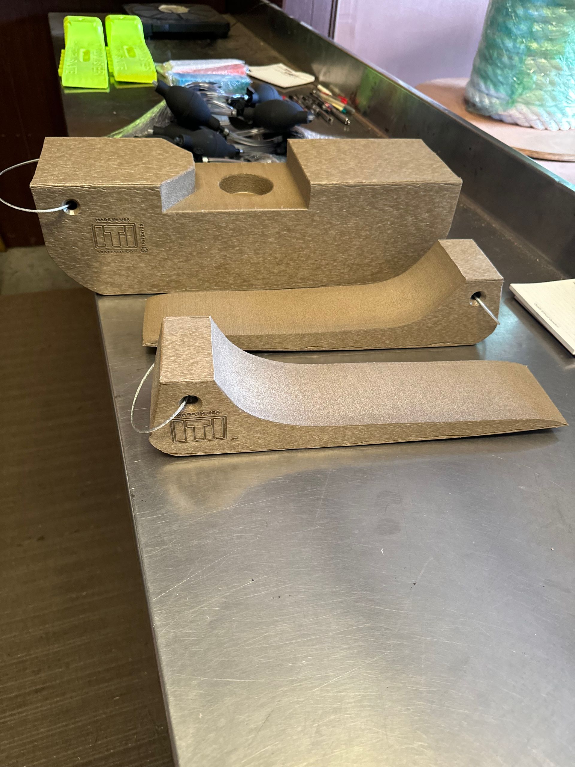 Two cardboard animal-shaped traps on a workbench, one upright and one lying flat, with tools in the background