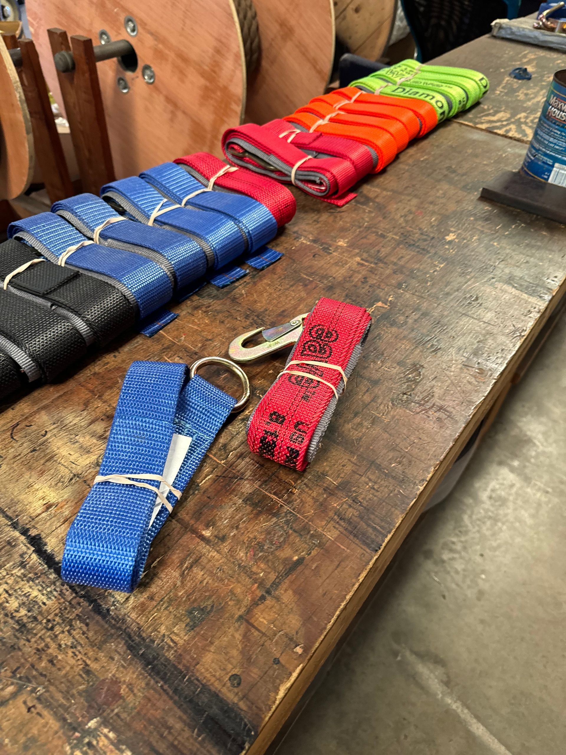 Colorful woven knife sheaths laid out on a wooden table at a market stall.