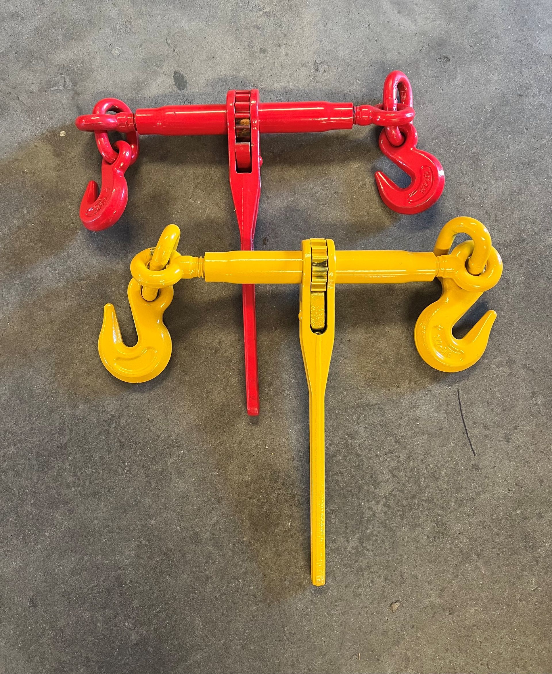 Two heavy-duty metal clamp spreaders, one red and one yellow, on a concrete floor.