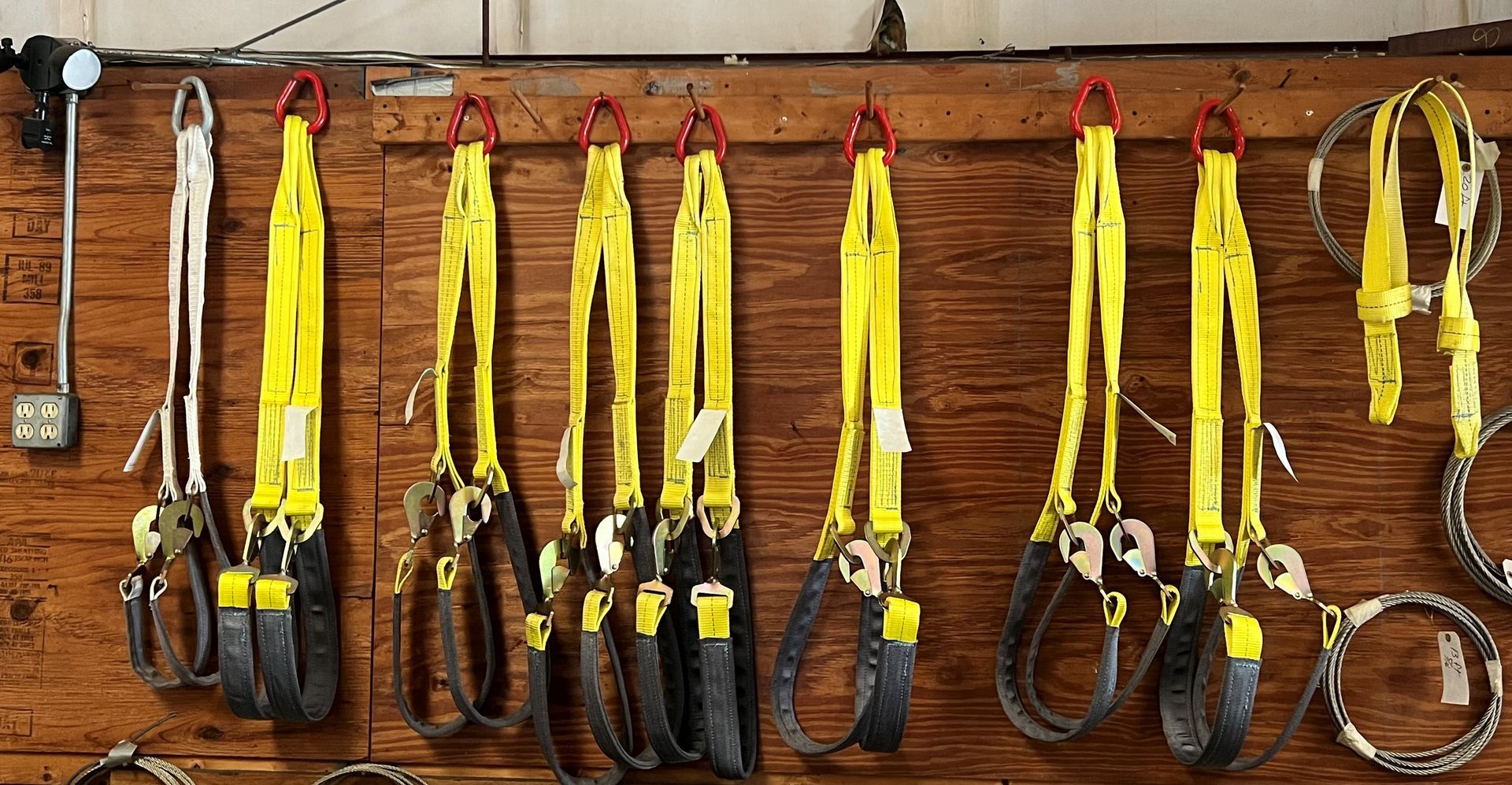 Assorted climbing harnesses and ropes hanging on a wooden wall in a gear shop