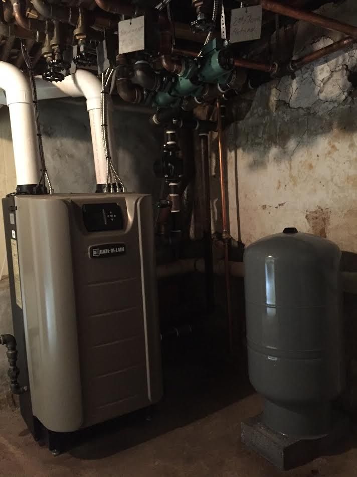 a boiler in a basement next to a water tank .