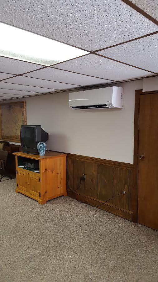 a room with a television and a air conditioner on the wall .