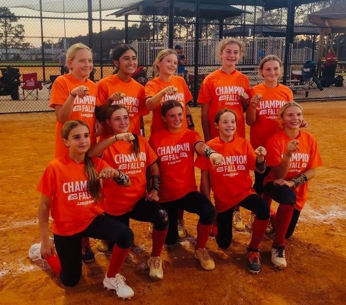 Softball team in orange shirts celebrating their championship win.