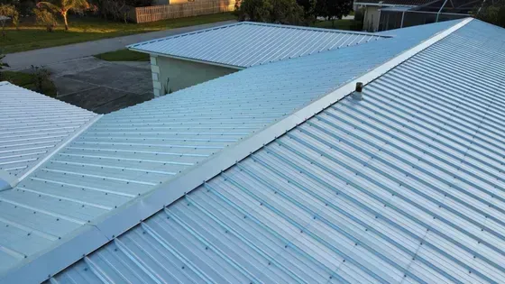 Metal roof with corrugated pattern, showing lines of silver panels, with light hitting it.