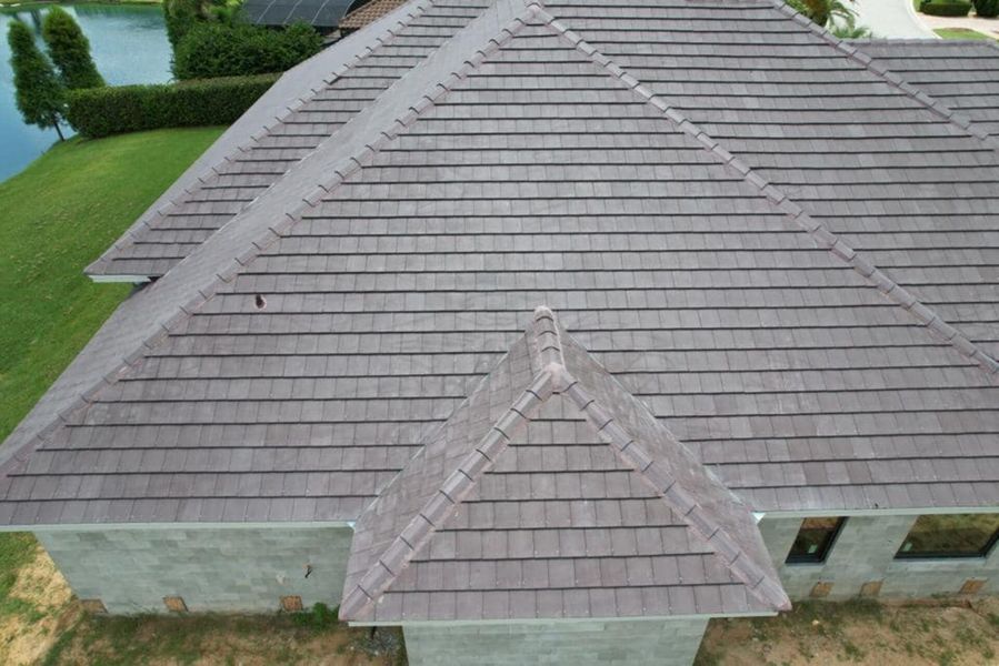 Gray roof of a house with multiple gabled sections, overlooking a lake and green lawn.