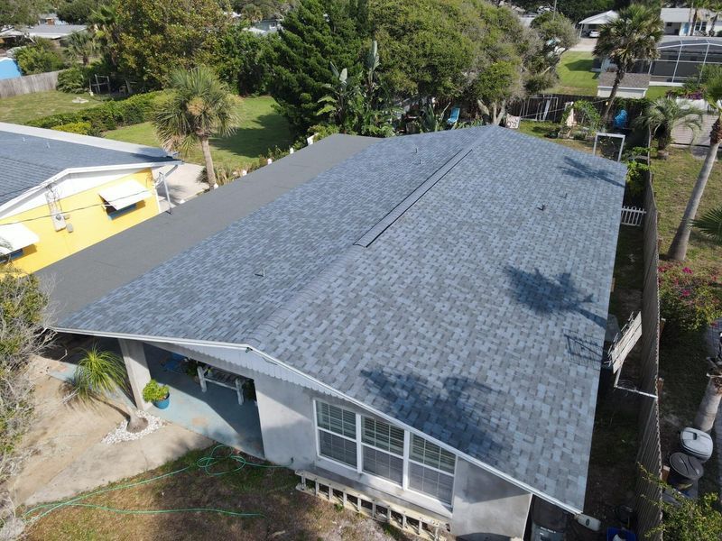 Aerial view of a house with a dark blue shingle roof.