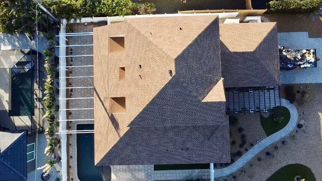 Overhead view of a house with a brown roof, pool, and pathway.
