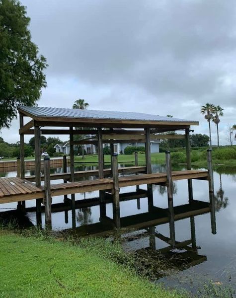 Wooden dock with a metal roof, on the water, cloudy sky.
