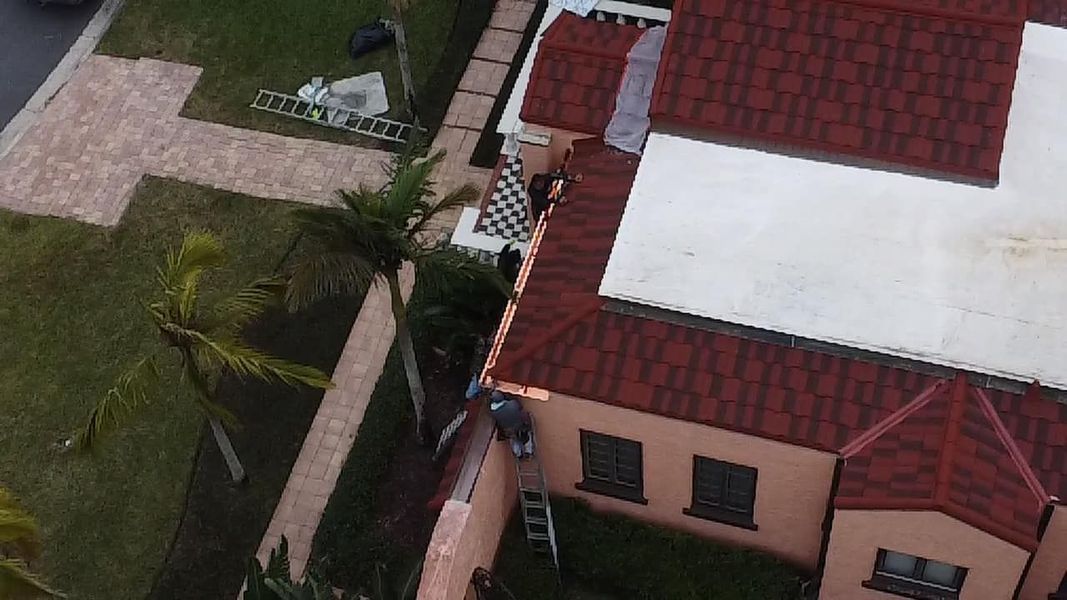 Overhead view of a house with red roof, adjacent to a walkway and a grassy yard.