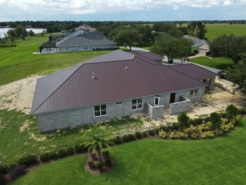 Brown-roofed house under construction in a green field.
