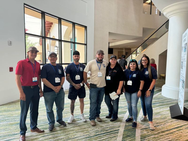 Group of people in casual attire posing at a conference, indoors.