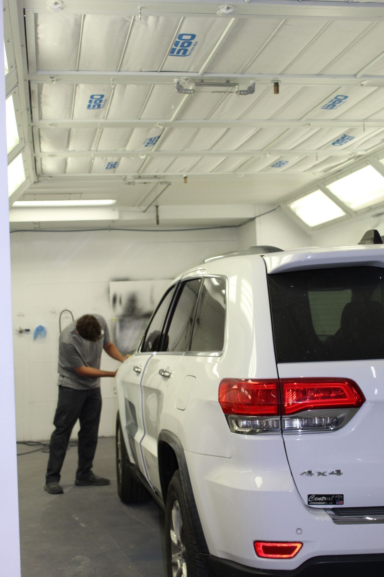 A man is standing next to a white suv in a garage.
